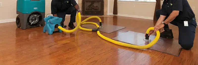 emergency water removal technicians extracting standing water from a home using professional equipment in Phoenix, AZ